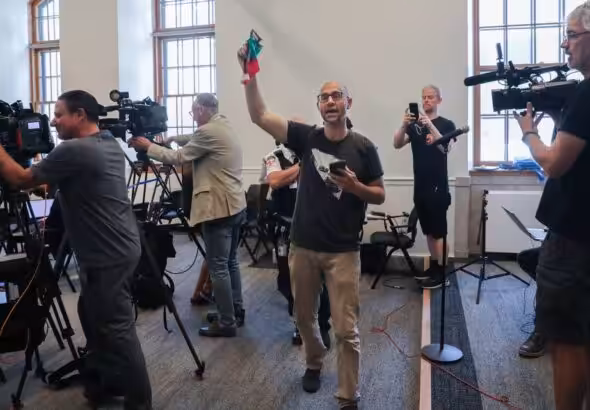 Yves Engler waves a Palestinian flag at Montreal Mayor Valérie Plante's press conference at Montreal city hall, July 5, 2024, protesting the police repression against a pro-Palestine encampment in Victoria Square. Photo: John Kenney/The Montreal Gazette.