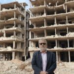 Dan Kovalik in front of the ruins of a buildings. Photo: Dan Kovalik/Covert Action Magazine.