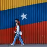 Two Venezuelans walk in front of their country's colors. Photo: Getty Images.