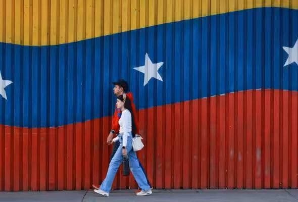 Two Venezuelans walk in front of their country's colors. Photo: Getty Images.