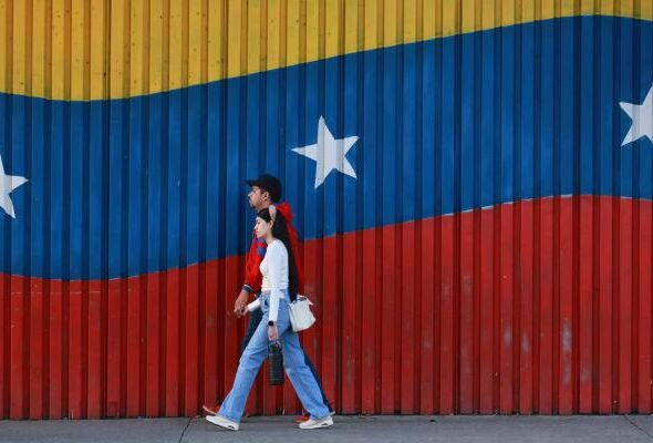 Two Venezuelans walk in front of their country's colors. Photo: Getty Images.