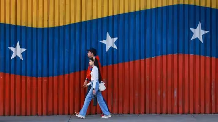 Two Venezuelans walk in front of their country's colors. Photo: Getty Images.