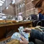 A teller counts US dollars at a commercial bank affiliated with the central bank in Damascus, December 16, 2024. Photo: Louai Beshara/AFP.
