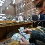 A teller counts US dollars at a commercial bank affiliated with the central bank in Damascus, December 16, 2024. Photo: Louai Beshara/AFP.