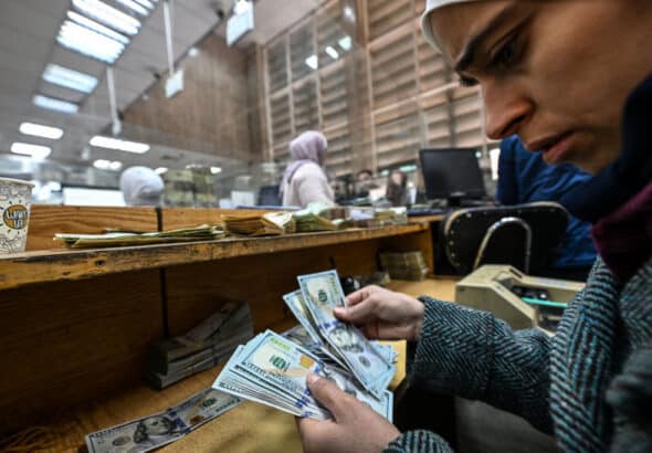 A teller counts US dollars at a commercial bank affiliated with the central bank in Damascus, December 16, 2024. Photo: Louai Beshara/AFP.