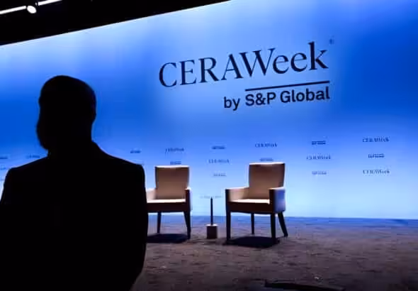 Silhouette of a passerby near the stage at the CERAWeek 2025. Photo: Bloomberg.