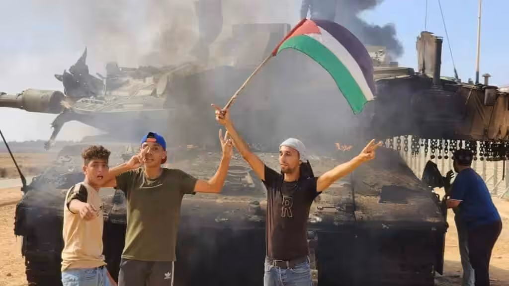 People waving a Palestinian flag in front of a destroyed Israeli tank. File photo.