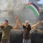 People waving a Palestinian flag in front of a destroyed Israeli tank. File photo.