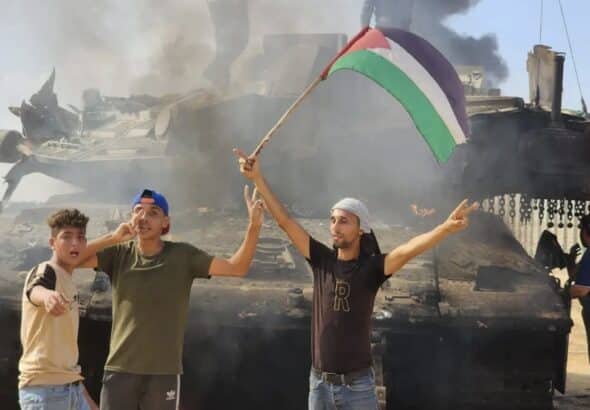 People waving a Palestinian flag in front of a destroyed Israeli tank. File photo.