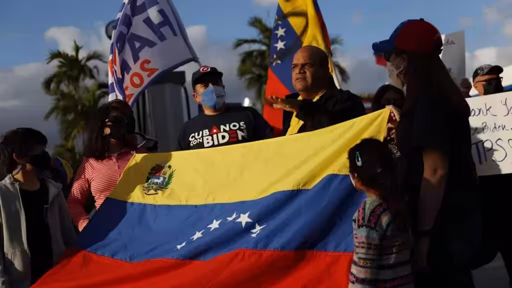 A group of Venezuelan migrants in Florida, USA, hold a Venezuelan flag and placards. Photo: BBC.