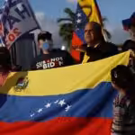 A group of Venezuelan migrants in Florida, USA, hold a Venezuelan flag and placards. Photo: BBC.
