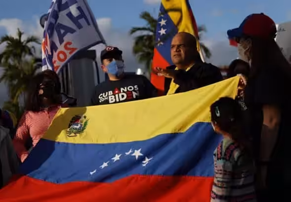 A group of Venezuelan migrants in Florida, USA, hold a Venezuelan flag and placards. Photo: BBC.
