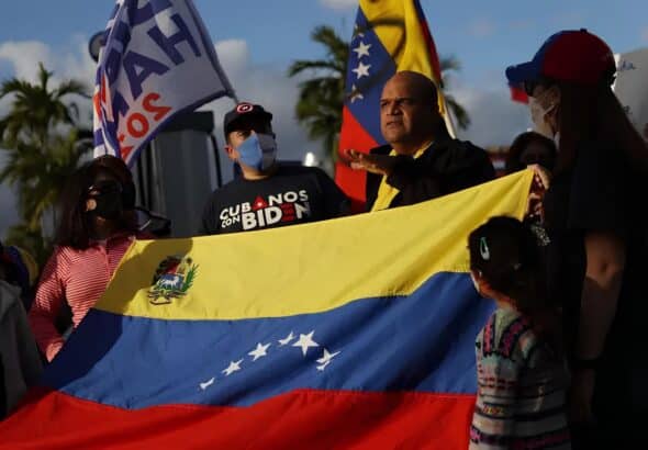 A group of Venezuelan migrants in Florida, USA, hold a Venezuelan flag and placards. Photo: BBC.
