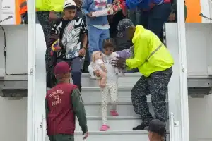 Venezuelan airline workers help a child returnee go down the steps of a repatriation flight from the US at the Simón Bolívar International Airport, April 4, 2025. Photo: AP/Ariana Cubillos.