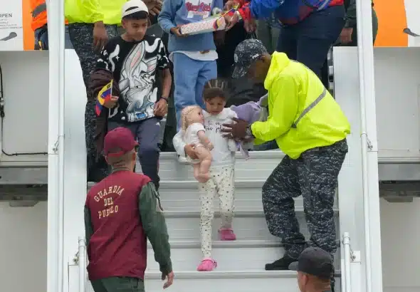 Venezuelan airline workers help a child returnee go down the steps of a repatriation flight from the US at the Simón Bolívar International Airport, April 4, 2025. Photo: AP/Ariana Cubillos.