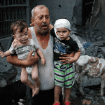 A Palestinian refugee carries his injured grandchildren from the Israeli bombing of Nuseirat Camp, Gaza Strip. Photo: Ashraf Amra/2023 UNRWA.