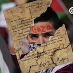 Photo composition showing a torn version of the Balfour Declaration superimposed over a photo of a youth holding a Palestinian flag and with the word "Gaza" written on his forehead. Photo: Al Mayadeen.