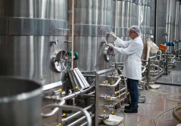 Factory worker monitoring a pressure gauge of a storage tank in a beer factory. Photo: Fluid Mac.