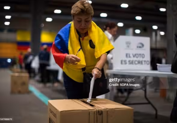 MADRID, SPAIN - 2024/04/21: A woman with an Ecuadorian flag around her neck casts her vote into the ballot box at one of the voting tables at the IFEMA fairgrounds in Madrid, during the referendum day in Ecuador. The Ecuadorian community registered in Madrid exceeds 60,000 and can exercise their right to vote for people from abroad, in the referendum proposed by President Daniel Noboa in the face of growing violence in Ecuador. Photo: Luis Soto/Getty Images.
