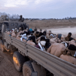 Israeli soldiers guard a vehicle containing bound and blindfolded Palestinian detainees in Gaza. Photo: Moti Milrod/AP.