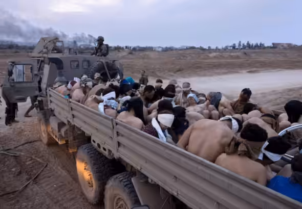 Israeli soldiers guard a vehicle containing bound and blindfolded Palestinian detainees in Gaza. Photo: Moti Milrod/AP.
