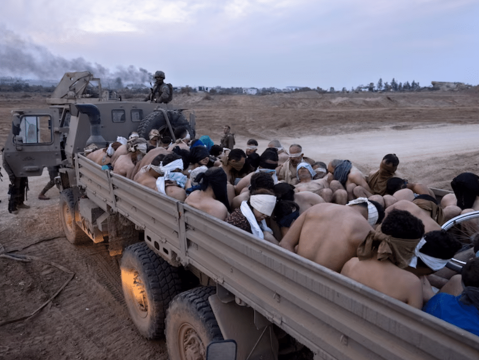 Israeli soldiers guard a vehicle containing bound and blindfolded Palestinian detainees in Gaza. Photo: Moti Milrod/AP.