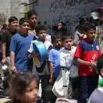 Dozens of children formed a long line outdoors, carrying containers such as pots, buckets, and makeshift containers to receive food. Photo: AFP.