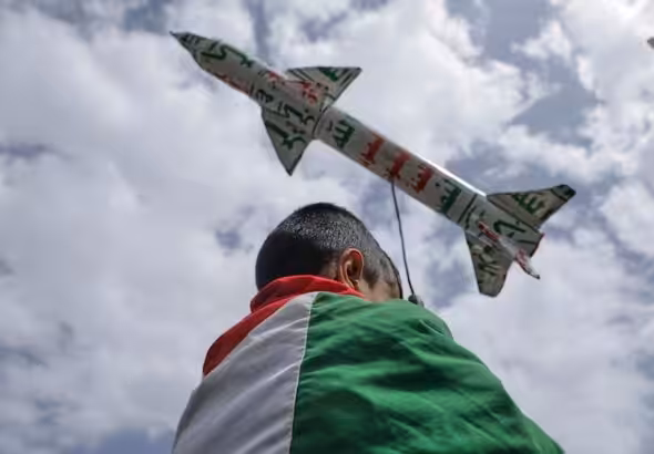 A boy draped in a Palestinian flag carries a mock rocket during a weekly anti-US and anti-Israeli rally in Sanaa, Yemen, Friday, May 9, 2025. Photo: Al Mayadeen.