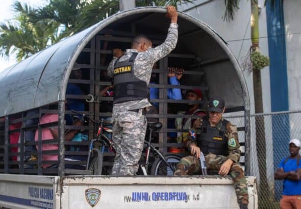 Dominican military personnel carry Haitian migrants rounded up in raids to a migrant detention center. Photo: EFE/Orlando Barria.