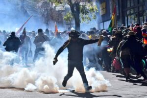 An Evo Morales supporter kicks a tear gas canister used by Bolivian police to repress those supporting Evo Morales registrations as candidate for the upcoming presidential elections. La Paz, Bolivia, on May 16, 2025. Photo: X/@evoespueblo.