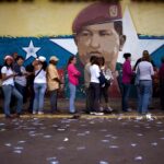 Line of voters in front of a wall bearing a mural of Hugo Chávez. Photo: AP/Ariana Cubillos/file photo.