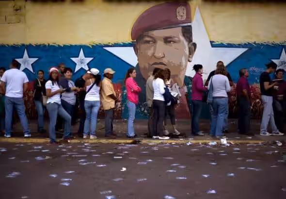 Line of voters in front of a wall bearing a mural of Hugo Chávez. Photo: AP/Ariana Cubillos/file photo.