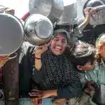 Palestinian children hold out pans to receive food. Photo: Anas Deeb/UPI.
