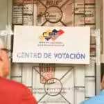 Two persons reading a National Electoral Council sign in front ot a voting center in Venezuela ahead of the May 25 elections. Photo: Telesur.
