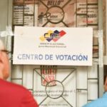 Two persons reading a National Electoral Council sign in front ot a voting center in Venezuela ahead of the May 25 elections. Photo: Telesur.