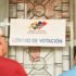 Two persons reading a National Electoral Council sign in front ot a voting center in Venezuela ahead of the May 25 elections. Photo: Telesur.