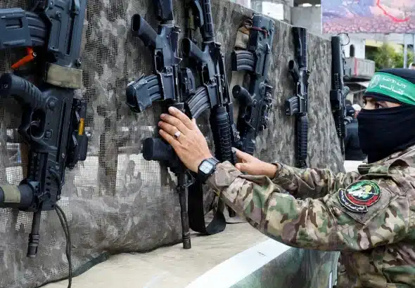 A fighter from the Qassam Brigades displays guns on the day of the handover of Israeli captives to members of the International Committee of the Red Cross in Rafah in the Gaza Strip, on 22 February 2025. Photo: Hatem Khaled/Reuters.