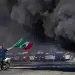 An anti-ICE protester waves a Mexican flag during violence in Los Angeles on Saturday. Photo: Reuters.