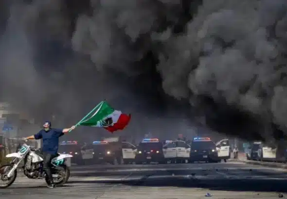 An anti-ICE protester waves a Mexican flag during violence in Los Angeles on Saturday. Photo: Reuters.
