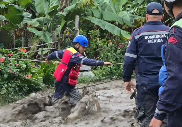 Emergency response agent crossing a creek during heavy rains in Merida state, Venezuela. Photo: IG/@nicolasmaduro.