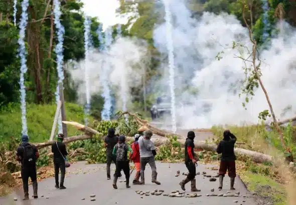 Protesters block a road with a tree trunk while police throw tear gas at them in Bocas del Toro province, Panama. Photo: EFE.