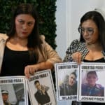 Relatives of Venezuelan migrants illegally imprisoned in El Salvador hold photos of their family members and demand their release. Photo: AFP.