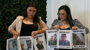 Relatives of Venezuelan migrants illegally imprisoned in El Salvador hold photos of their family members and demand their release. Photo: AFP.