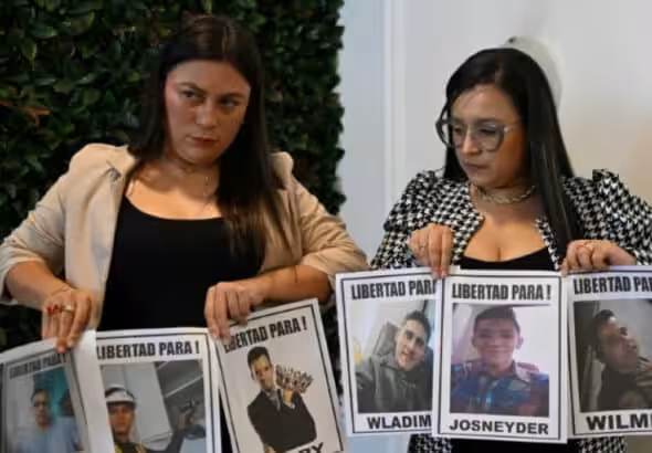 Relatives of Venezuelan migrants illegally imprisoned in El Salvador hold photos of their family members and demand their release. Photo: AFP.
