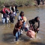 Alawite Syrians, who fled the violence in western Syria, walk in the water of the Nahr El Kabir River, after the mass killings of Alawite minority members, in Akkar, Lebanon on March 11, 2025. Photo: Reuters.