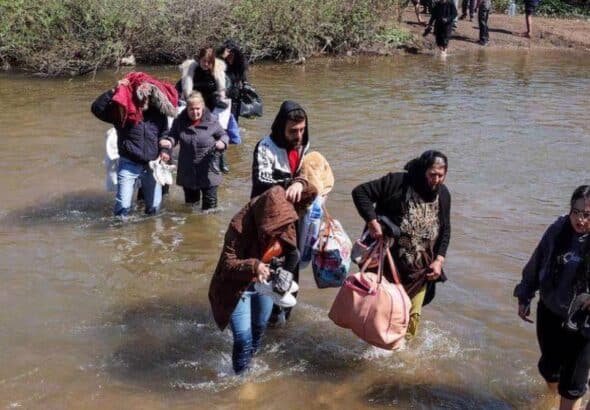 Alawite Syrians, who fled the violence in western Syria, walk in the water of the Nahr El Kabir River, after the mass killings of Alawite minority members, in Akkar, Lebanon on March 11, 2025. Photo: Reuters.
