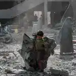 A Palestinian child carries a tent through rubble in Gaza City, June 30, 2025. Photo: AFP.