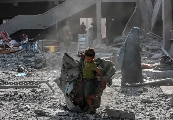A Palestinian child carries a tent through rubble in Gaza City, June 30, 2025. Photo: AFP.