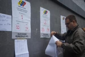 A man places the voting list at a polling station in Caracas this Sunday. Voting centers began opening their doors this Sunday in Venezuela. Photo: Boris Vergara/EFE.