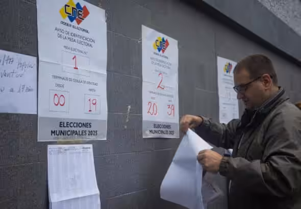 A man places the voting list at a polling station in Caracas this Sunday. Voting centers began opening their doors this Sunday in Venezuela. Photo: Boris Vergara/EFE.